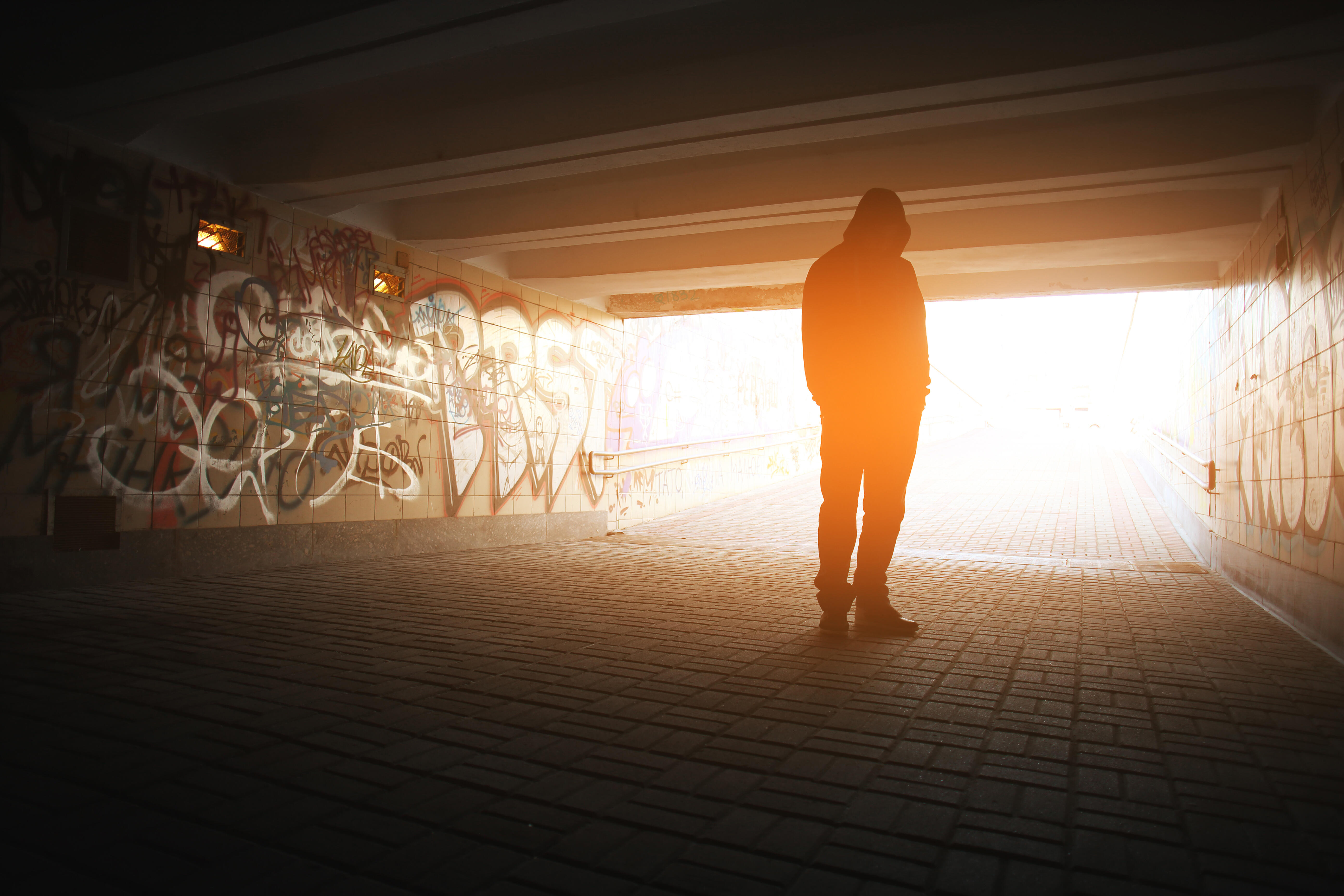 Depressed person stands under a bridge.